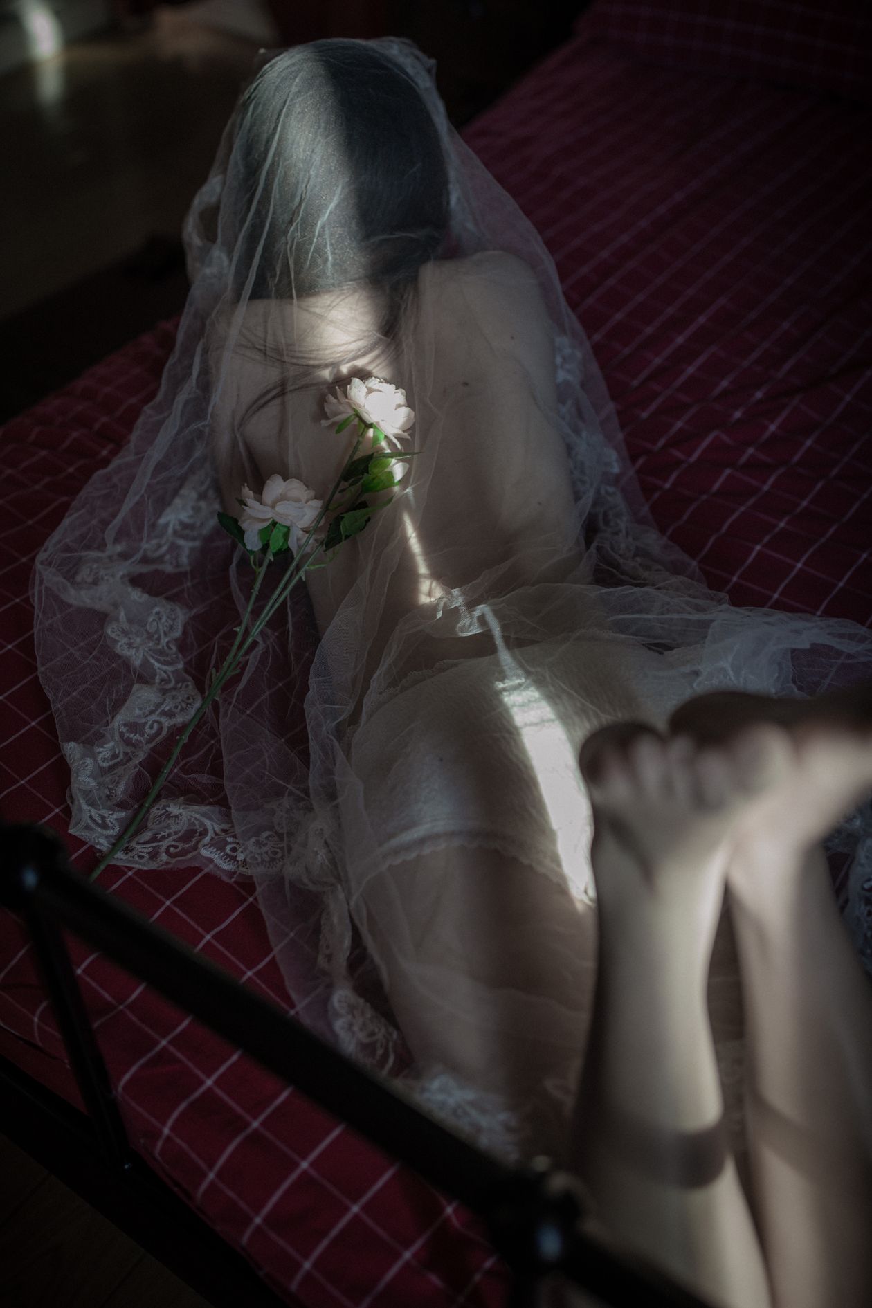 Woman in white lingerie and a veil lying on a bed