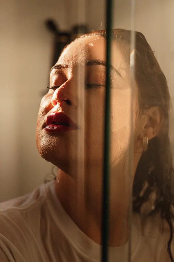 Woman in a cinematic wet-look shower portrait