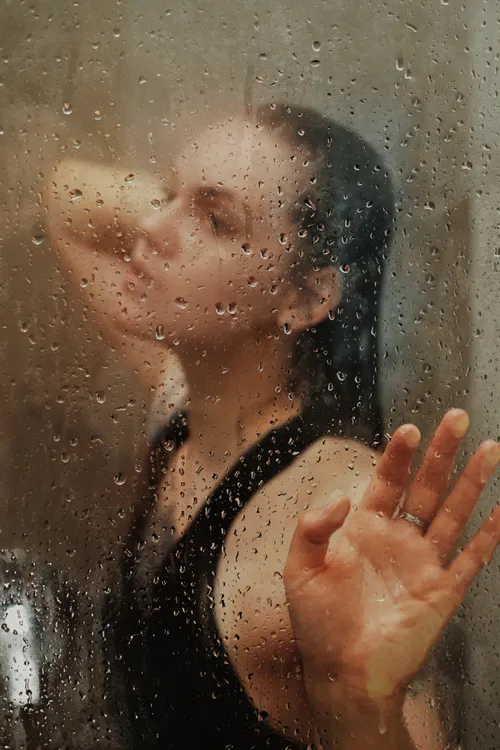 Close portrait of a woman seen through wet glass