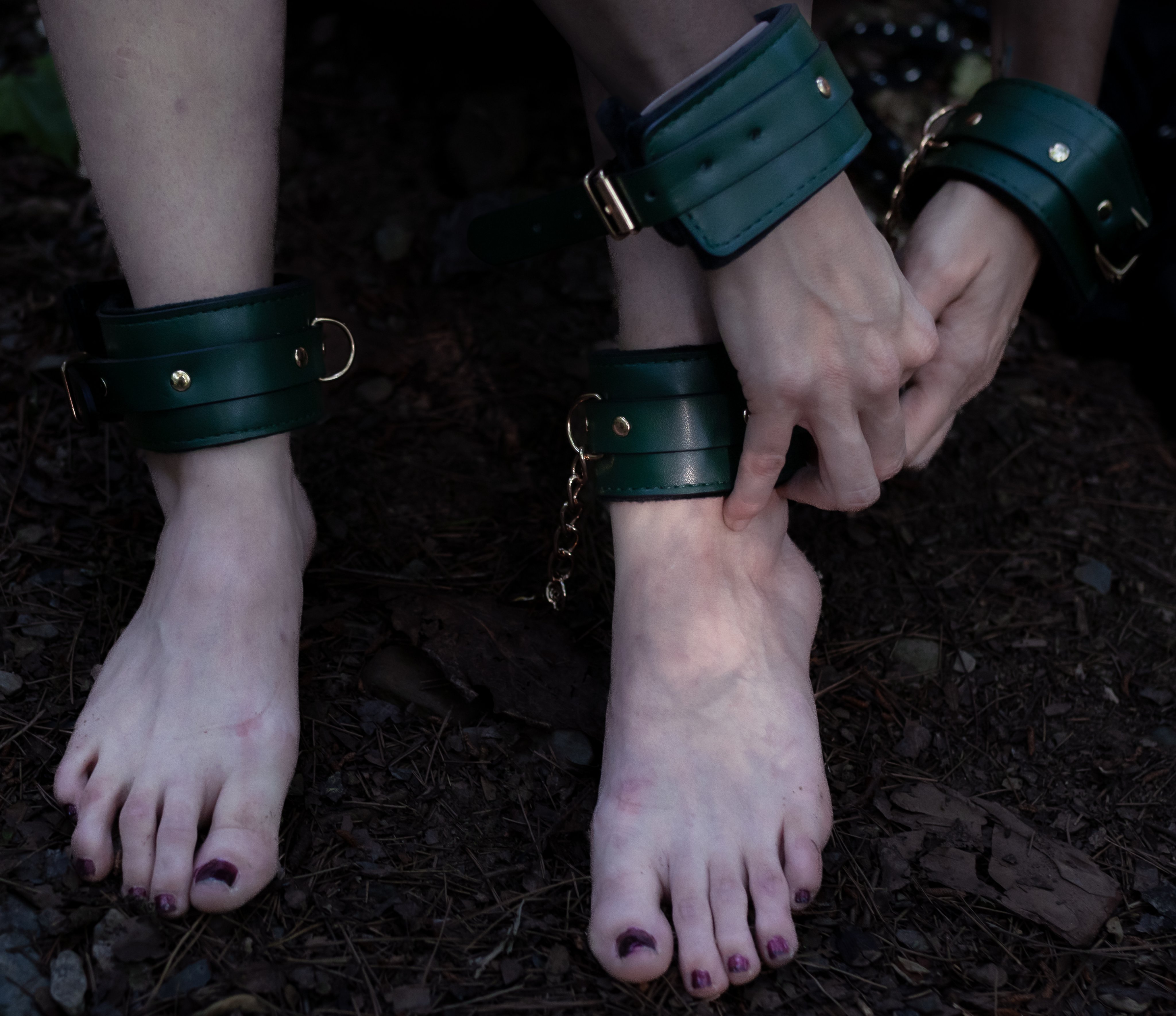 Bound hands and feet in dark green leather cuffs with chains