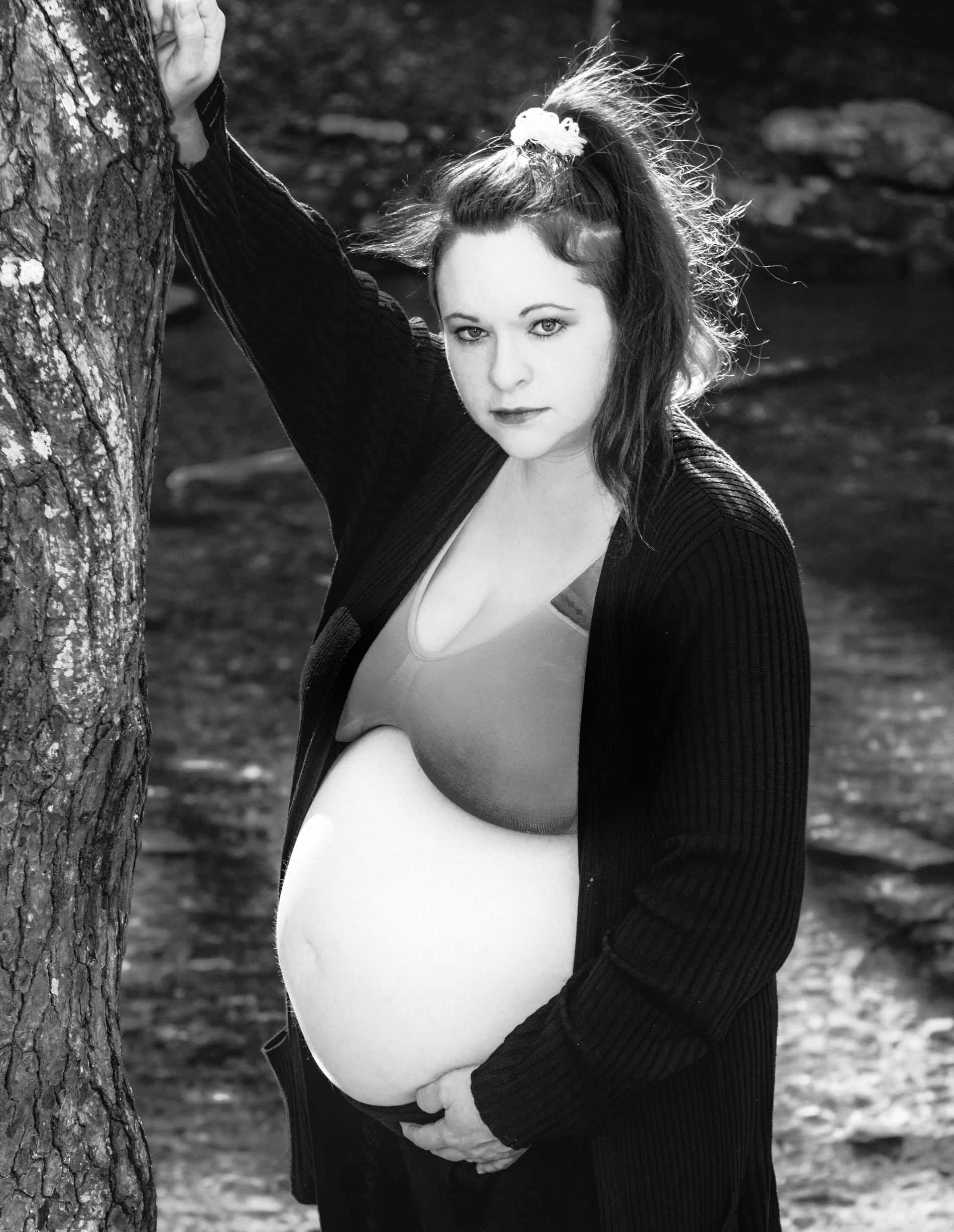 Black-and-white outdoor maternity portrait beside a tree